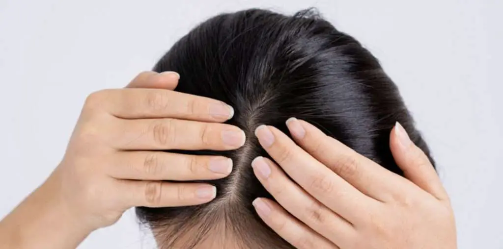Woman checking her scalp to remove build up from hair
