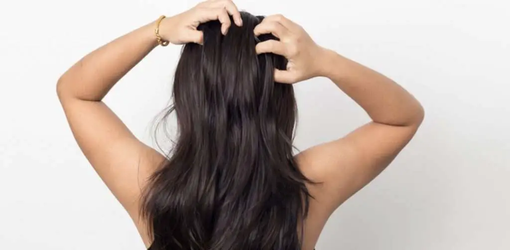 Woman touching her hair to tell if it is greasy