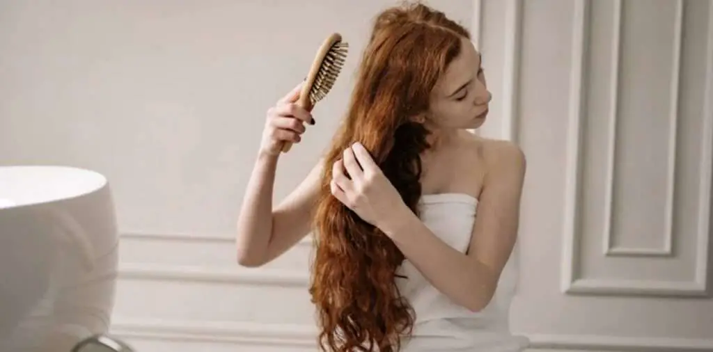 Woman brushing her long hair in the bathroom